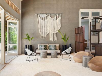 Coin salon moderne avec mur gris, décoration en macramé et accès ouvert à la terrasse.