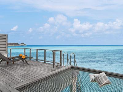 Terrazza con lettini in legno e vista diretta sul mare con cielo limpido.