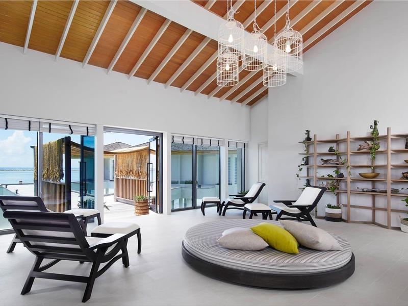 Area lounge luminosa con mobili moderni, grande divano rotondo e vista sul mare.