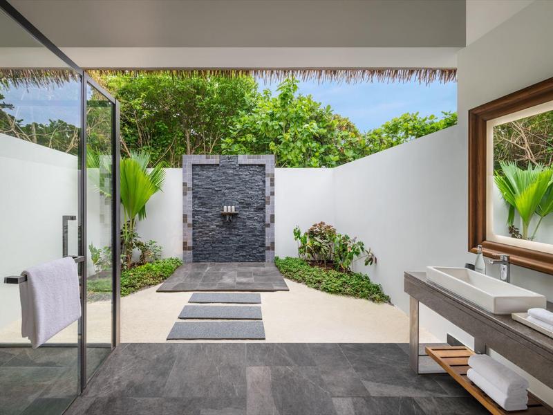 Area esterna moderna con doccia libera, pavimento in pietra naturale e grandi specchi accanto al lavandino.