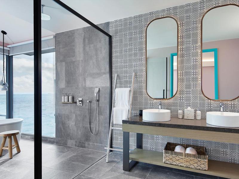 Bagno moderno con doppi lavandini e ampia doccia in vetro con vista sul mare.