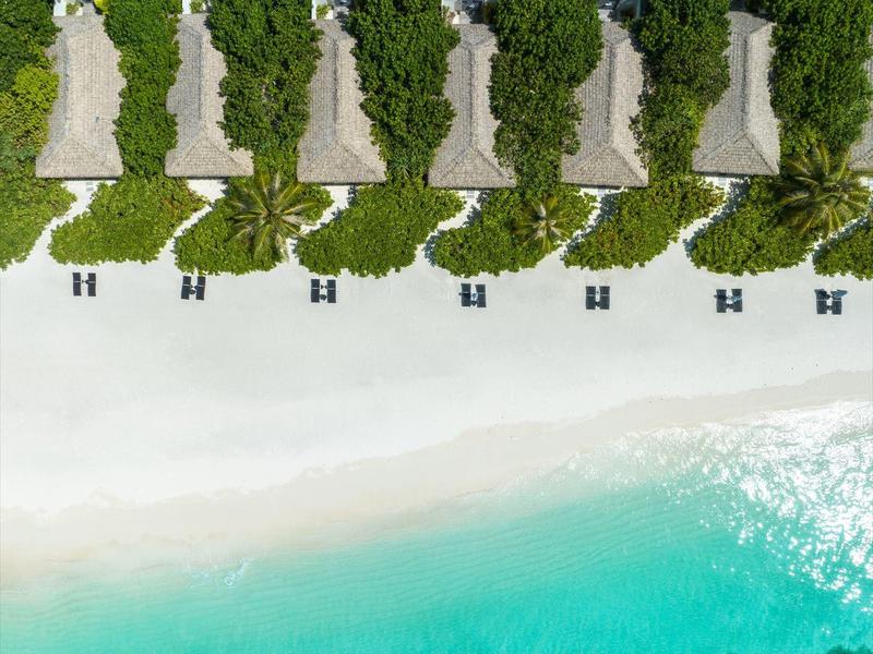 Sei capanne di paglia tradizionali sulla spiaggia con acqua turchese e foresta verde