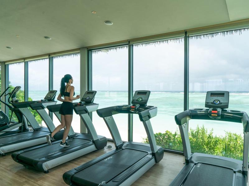 Palestra moderna con diversi tapis roulant e grandi finestre panoramiche con vista sul mare.