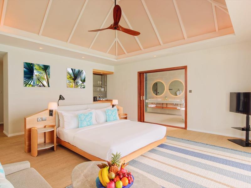 Helles Schlafzimmer mit großem Bett, Holzdecke, Kunst an der Wand und Glas-Schiebetür zum Bad.