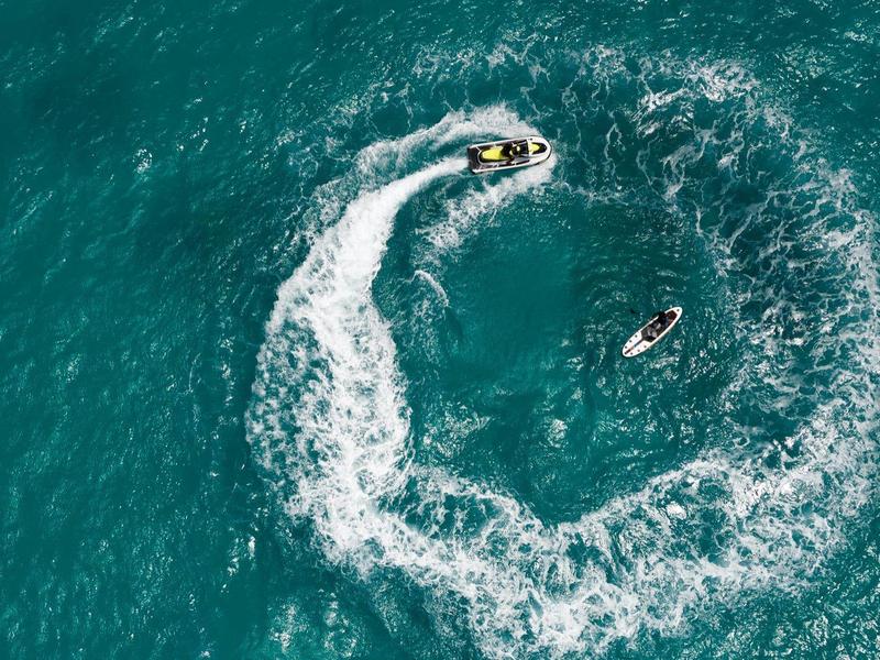 Persona en jetski haciendo movimientos circulares en el agua azul del mar durante una actividad de ocio.