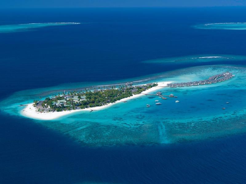 Toma aérea de una isla tropical con arena blanca y agua turquesa en el mar.