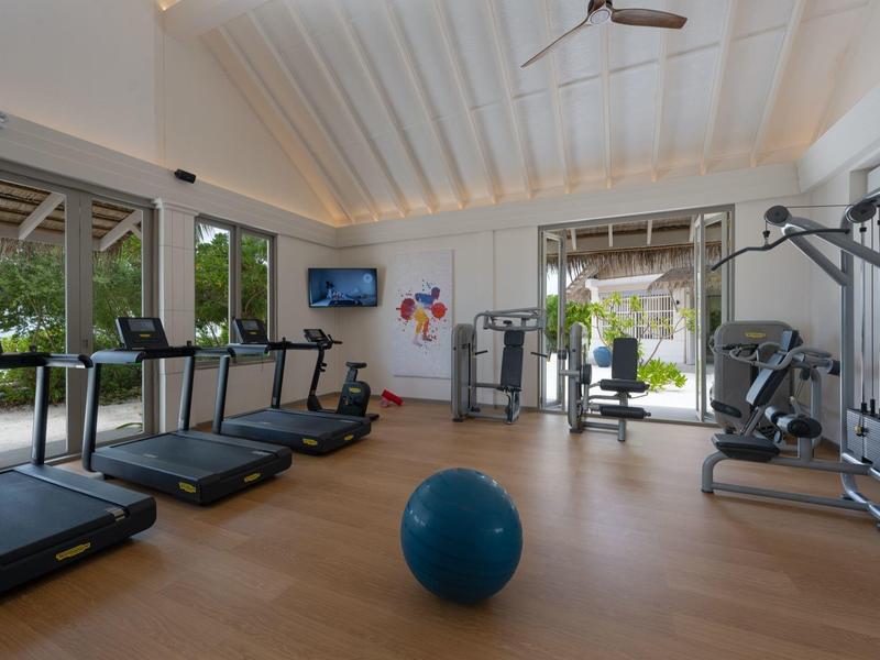 Gimnasio moderno con equipos de entrenamiento, cintas de correr y gran pelota de gimnasia en un espacio luminoso.