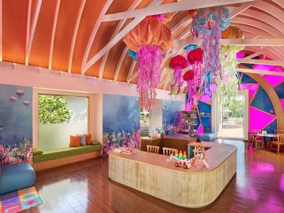 Vestíbulo de hotel moderno y colorido con obras de arte y iluminación decorativa.