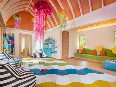 Habitación colorida para niños con muebles vibrantes, juguetes colgantes y alfombra con ondas.