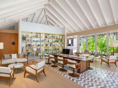 Sala moderna con techo blanco alto y grandes ventanas con vistas a la vegetación.