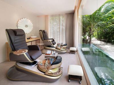 Reposeras modernas de spa con taburetes blancos junto a una gran ventana con vista a plantas tropicales