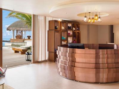 Moderna zona de recepción con mostrador redondo de madera y vista a una terraza con vista a la playa.