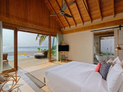 Chambre d'hôtel avec grande baie vitrée donnant sur une terrasse avec vue sur la mer.