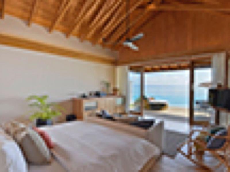 Chambre moderne avec plafond en bois et grande baie vitrée donnant sur la mer