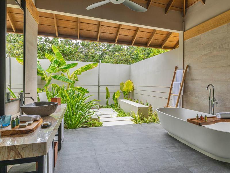 Espace de salle de bain moderne avec baignoire indépendante donnant sur un jardin verdoyant.