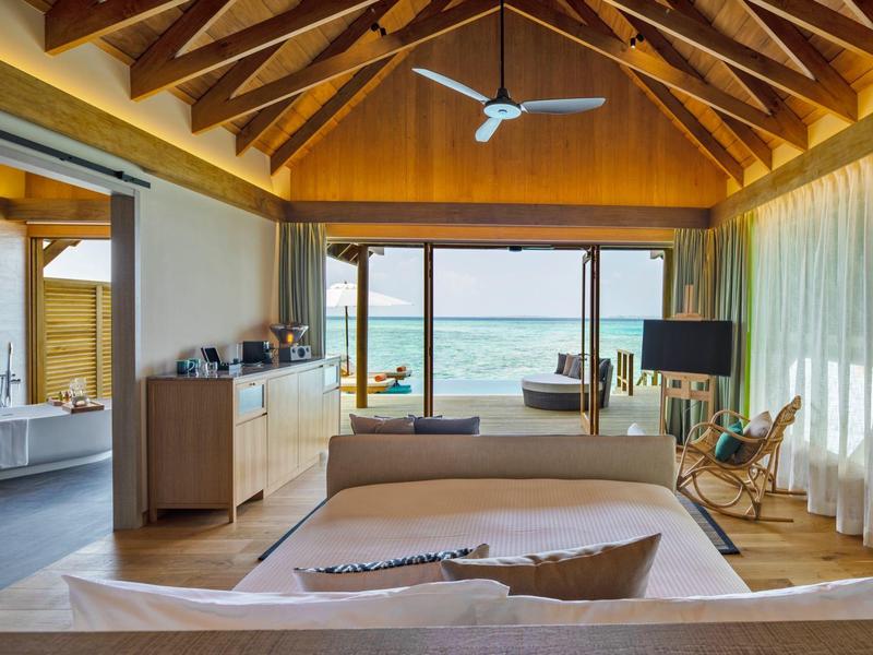 Villa de luxe en bord de mer avec salon ouvert, plafond en bois et vue sur la mer.