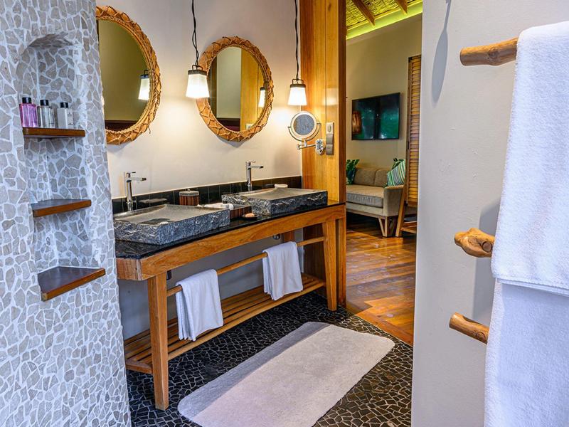 Modern bathroom with wooden vanity, two round mirrors, and hanging lights.