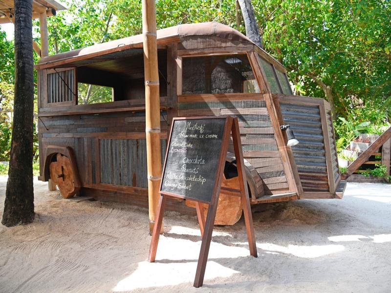 Rustic wooden trailer converted into a small outdoor bar surrounded by trees.