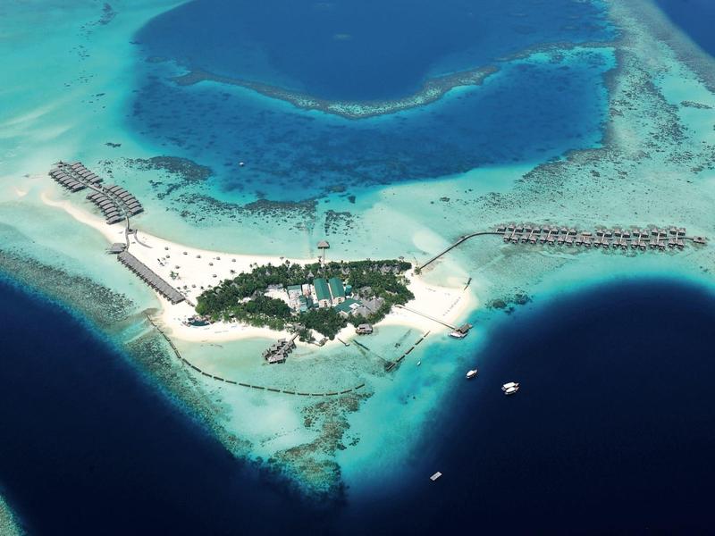 Aerial view of a tropical island resort with white sandy beaches and turquoise waters.