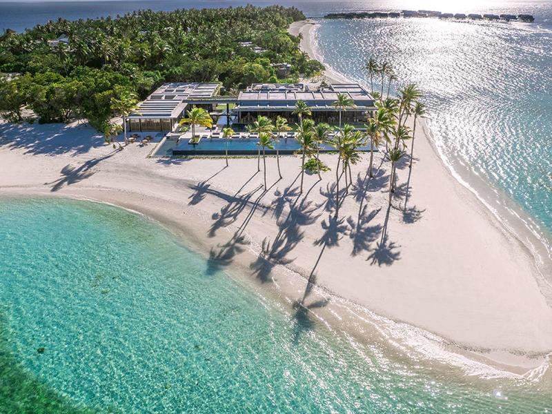 Tropikalna wyspa z palmami, białą piaszczystą plażą i krystalicznie czystą turkusową wodą.