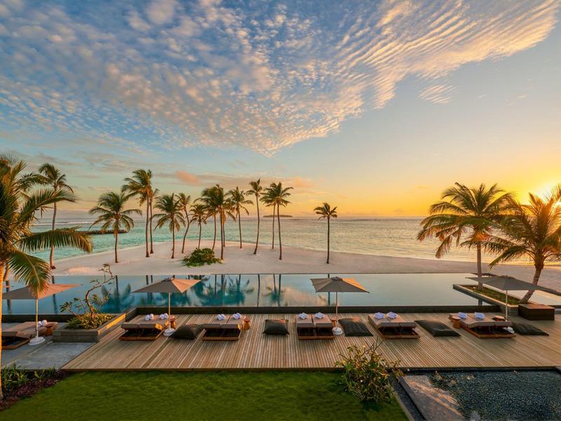 Basen infinity z tarasem słonecznym i palmami o zachodzie słońca w tropikalnym hotelu