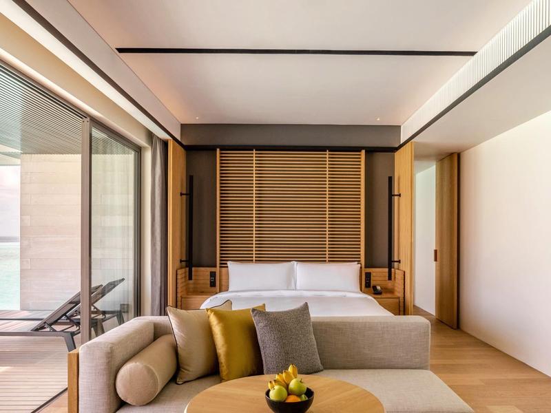 Nowoczesny pokój hotelowy z podwójnym łóżkiem, sofą, drzwiami na balkon i widokiem na morze.