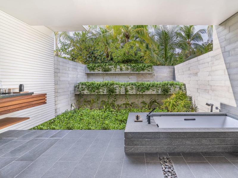 Nowoczesna łazienka na zewnątrz z wolnostojącą wanną i zielonym dachem w naturalnym otoczeniu.
