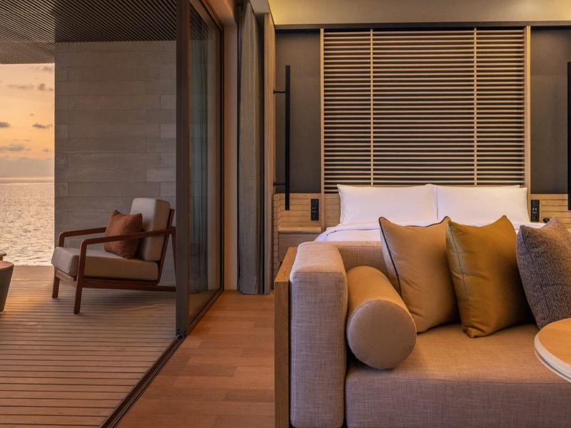 Nowoczesny taras hotelowy z miejscem do siedzenia i widokiem na morze o zachodzie słońca.