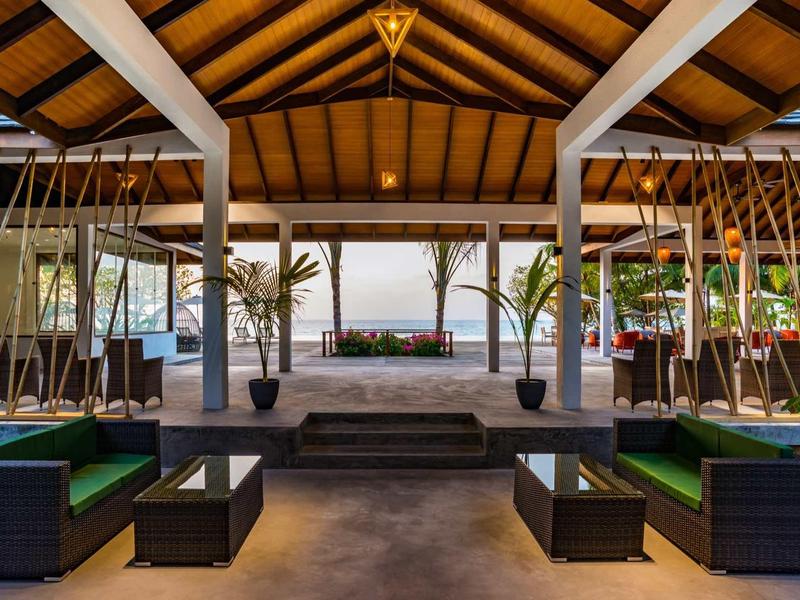 Open lounge area with modern seating and sea view under wooden beam ceiling