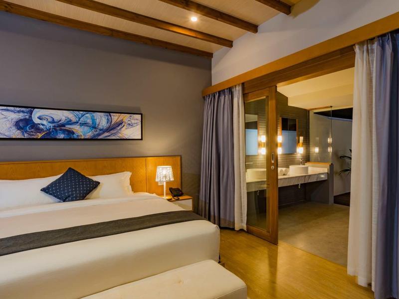 Modern hotel room with large bed and open bathroom area.