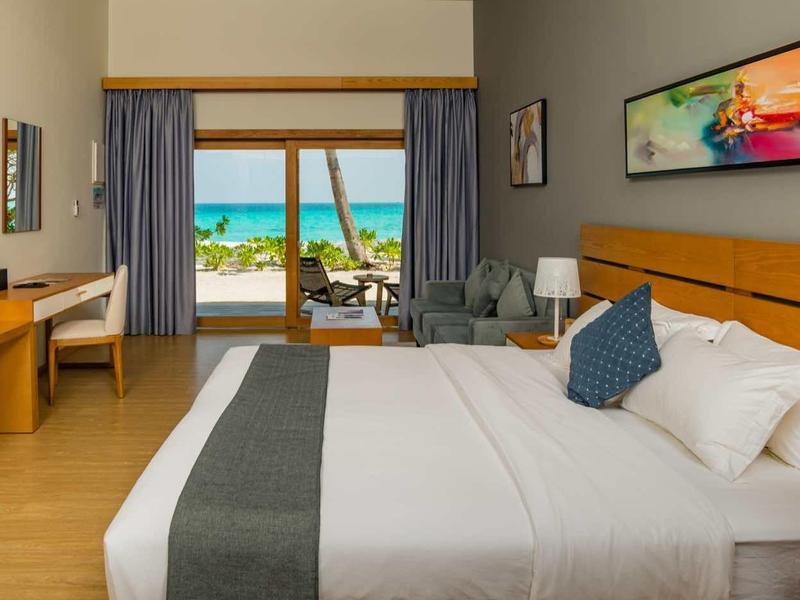 Modern hotel room with large windows overlooking the beach and sea.