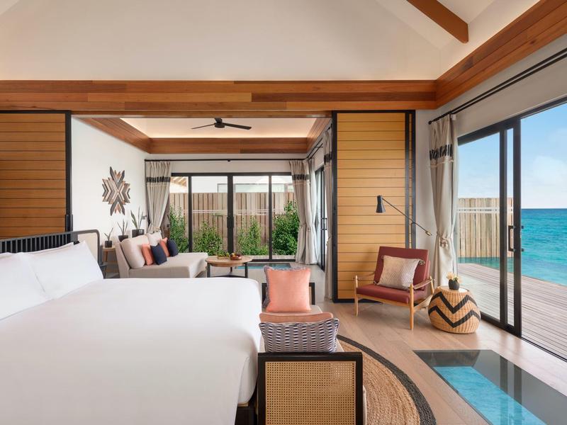 Chambre d'hôtel moderne avec grandes fenêtres, piscine attenante et vue sur la mer.