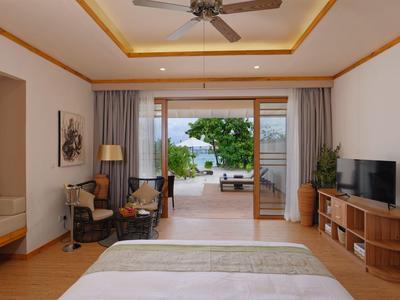 Chambre d'hôtel moderne avec vue sur la mer, bureau, TV et coin salon confortable.