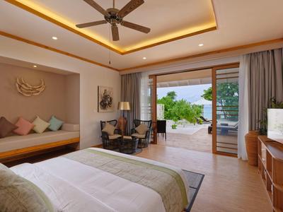 Chambre d'hôtel moderne avec lit double, coin salon et accès à une terrasse avec vue sur la mer.