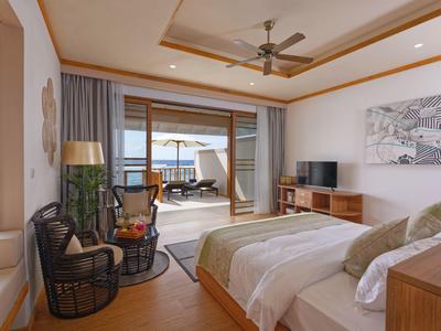 Chambre d'hôtel lumineuse avec lit double, meubles en bois et vue sur une terrasse.