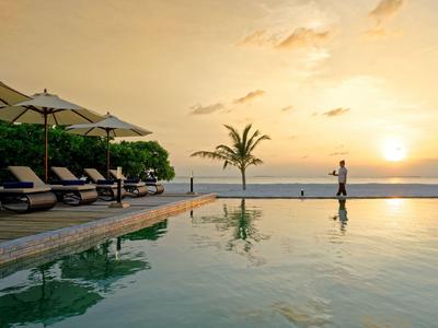 Coucher de soleil à la piscine avec chaises longues et un palmier au bord de la mer