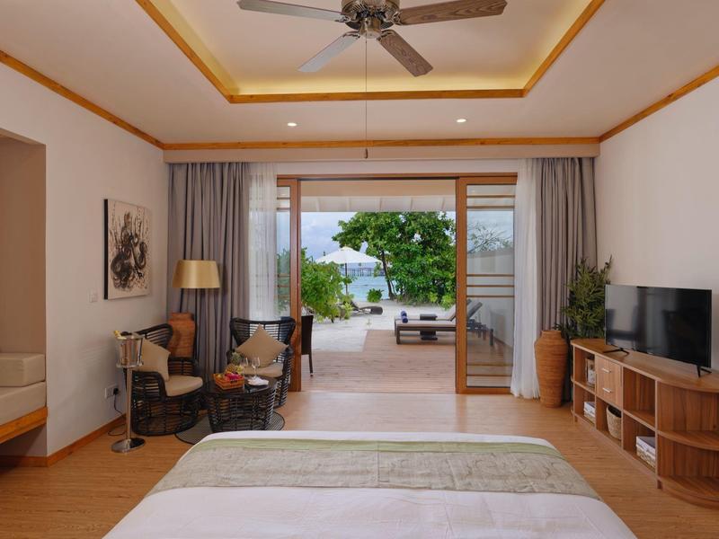 Chambre d'hôtel moderne avec vue sur la mer, bureau, TV et coin salon confortable.