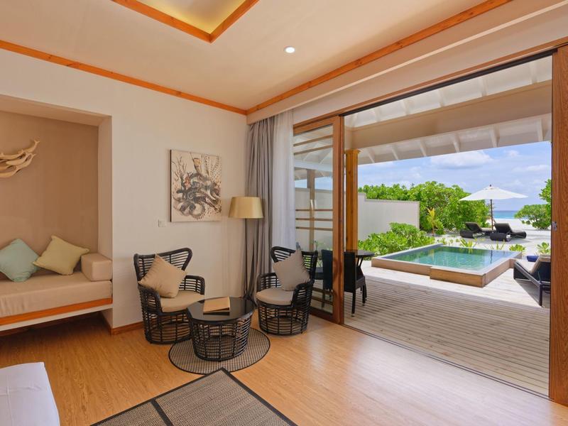 Salon lumineux avec accès à la terrasse et piscine, mobilier moderne et plafond décoratif.