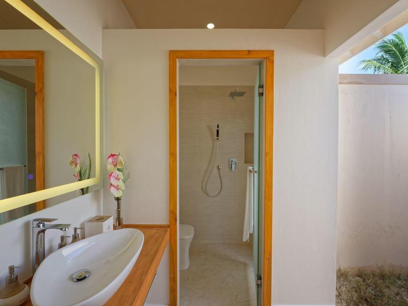 Salle de bain moderne avec lavabo, miroir éclairé et douche à l'italienne avec porte en verre.