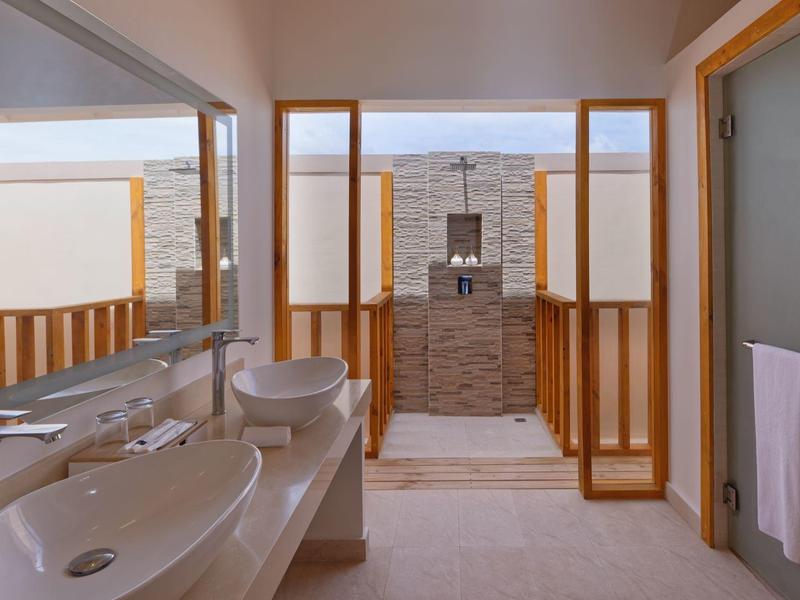 Salle de bain moderne avec deux vasques et douche indépendante encadrée de bois.