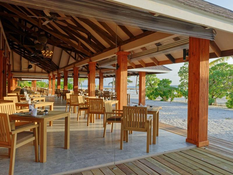 Espace repas ouvert avec mobilier en bois et vue sur jardin verdoyant à la lumière du jour.