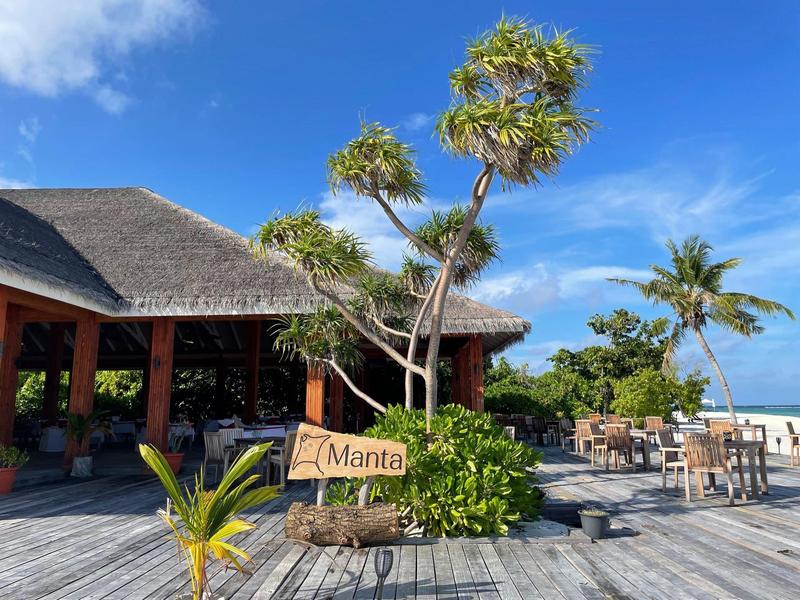 Restaurant ouvert au toit de chaume avec panneaux et cadre tropical en bord de plage