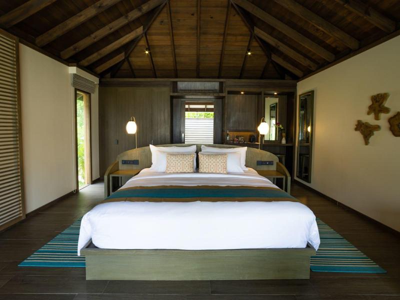 Chambre moderne avec grand lit et plafond en bois dans une chambre d'hôtel.