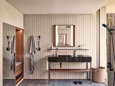 Modern hotel bathroom area with mirror, double sinks, and towels on the wall.