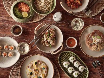 Various Asian dishes artfully arranged on plates on a wooden table.