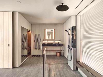 Modern bathroom with illuminated mirror, rain shower, and wooden accents.