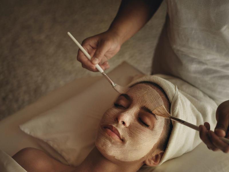 Woman receiving facial treatment with brush in spa setting