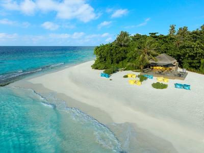 Tropical beach with clear water, white sand, and colorful beach bar in green surroundings.