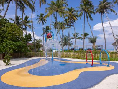 Small colorful children's splash pool with water features under palm trees by the beach.