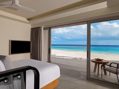 Modern hotel room overlooking white sandy beach and turquoise sea.